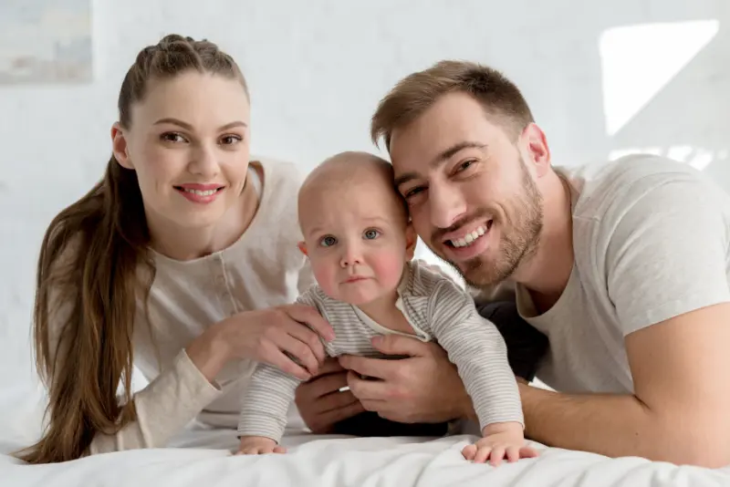 smiling parents with little boy on bed